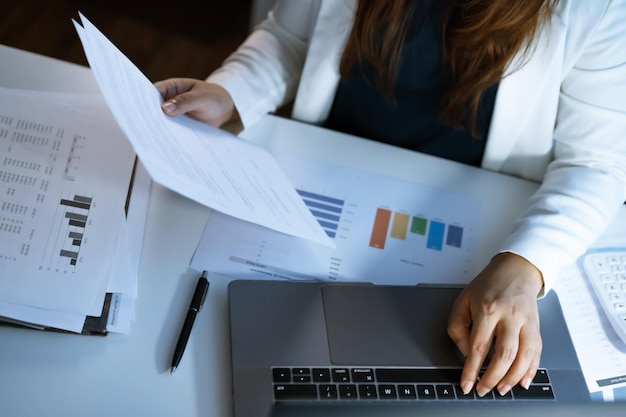 Solo trabajando tarde en la noche Mujer de negocios asiática en el lugar de trabajo en la oficina trabajo nocturno en un escritorio en una oficina oscura trabajando en una computadora portátil tarde en la noche