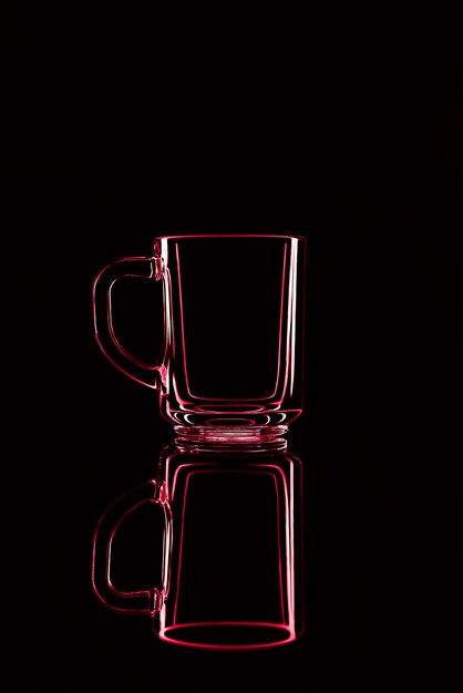 Solo un vaso sobre un fondo negro con un reflejo. Colores rojos. Aislado.