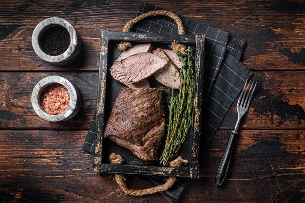 Solomillo de bistec Tri Tip a la parrilla en una bandeja con hierbas Fondo de madera Vista superior