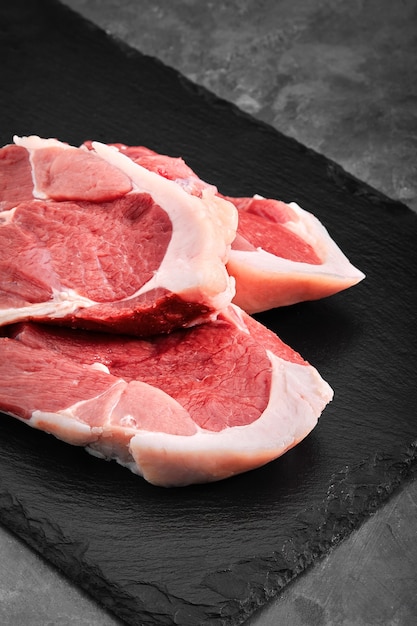 Solomillo de cerdo Dos trozos de carne de cerdo en una placa de pizarra sobre una mesa gris
