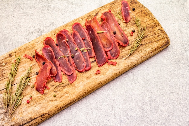 Foto solomillo seco de carne de res con romero seco y mezcla de pimienta sobre tabla de madera vintage