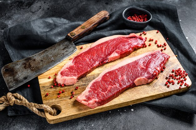 Solomillo de ternera sobre una tabla para cortar. Carne de res orgánica. Superficie negra. Vista superior