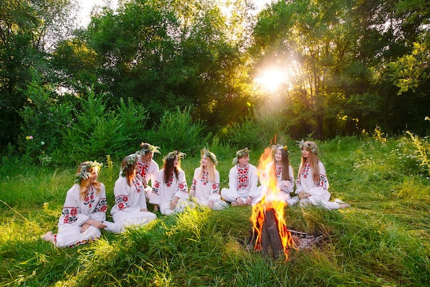 Solstício de verão, grupo de jovens de aparência eslava estão sentados ao redor de uma fogueira.