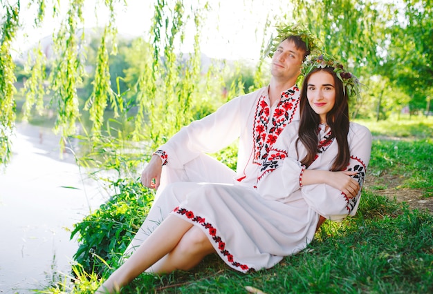 Solstício de verão. Jovem casal apaixonado em trajes eslavos na margem do lago. Férias eslavas de Ivan Kupala.