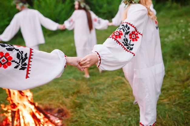 Solstício de verão. jovens em roupas eslavas giram em torno de um incêndio no solstício de verão. .