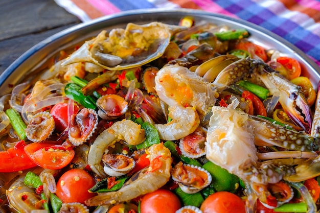 Som Tam Seafood (scharfer Papaya-Salat) mit gesalzener Krabbe, auf Holztisch (thailändisches Essen)