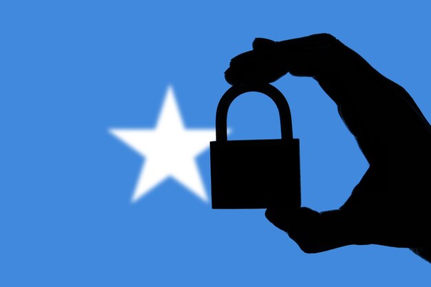 Somalia-Sicherheit Silhouette einer Hand, die ein Vorhängeschloss über der Nationalflagge hält