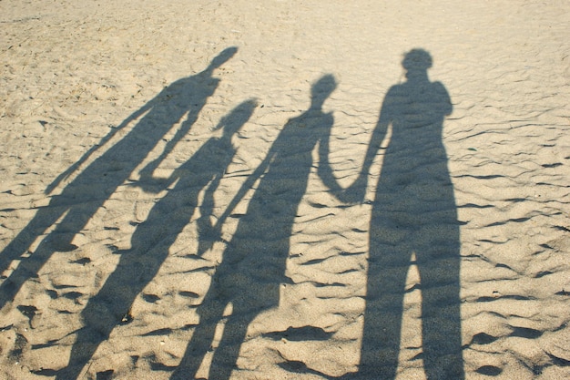 Sombra en la arena de la familia, padres e hijos cogidos de la mano.