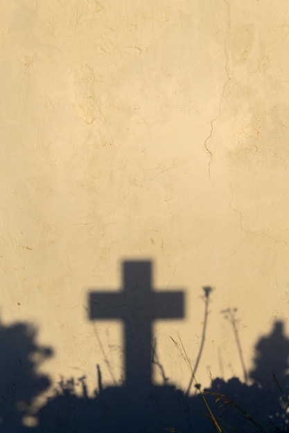 Sombra de una cruz en una tumba en un cementerio griego al amanecer