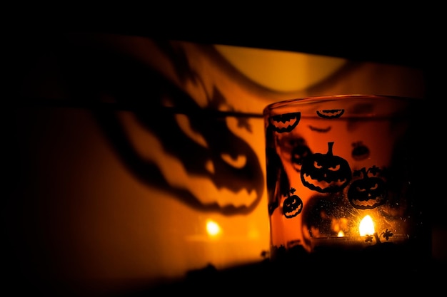 Foto sombra de abóbora de halloween iluminada por uma vela em um ambiente escuro de horror de vidro