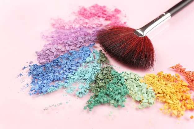 Sombra de arco-íris esmagada e pincel de maquiagem profissional em fundo rosa