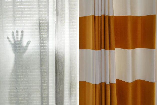 Foto sombra de pessoa atrás da cortina em casa