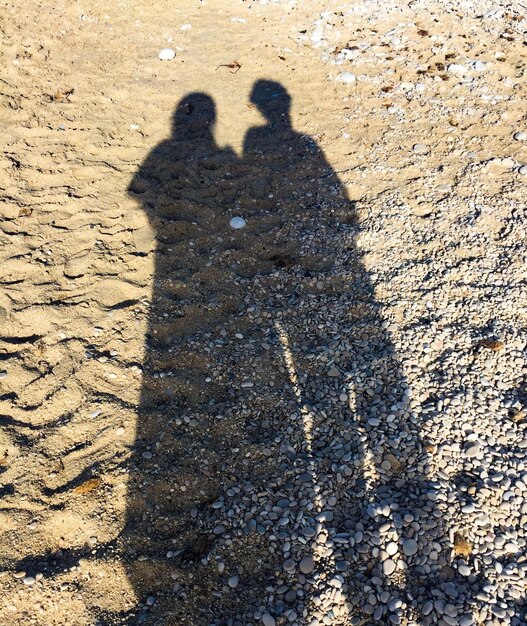 Foto sombra de um casal na praia de areia durante um dia ensolarado