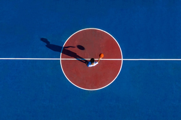 Foto sombra de um jovem macho apto a jogar basquete em uma quadra ao ar livre