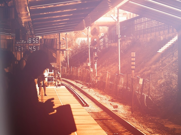 Sombra do homem na estação de trem durante o pôr do sol