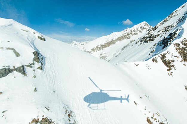 Sombra de helicóptero proyectada sobre la nieve en las crestas de las montañas