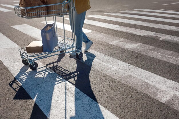 La sombra de la mujer camina con carrito de compras en el cruce peatonal marcado