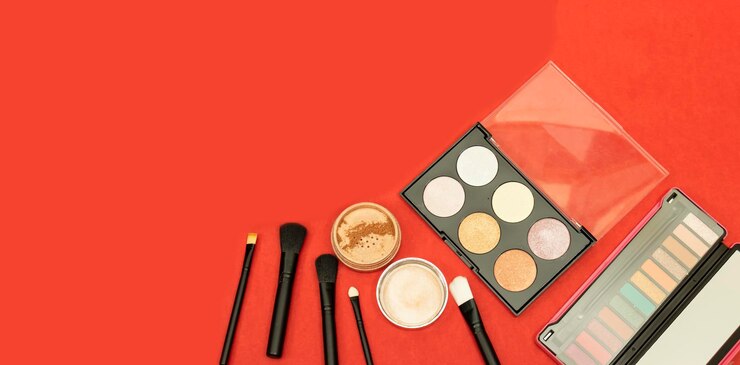 Foto sombra de ojos colorida y rubor destacador de fundación y pinceles con espacio de copia en fondo rojo