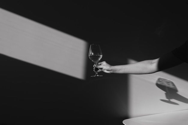 Sombra en la pared de una sommelier femenina con una copa de vino Silueta de una niña bebiendo vino Claroscuro desde la ventana