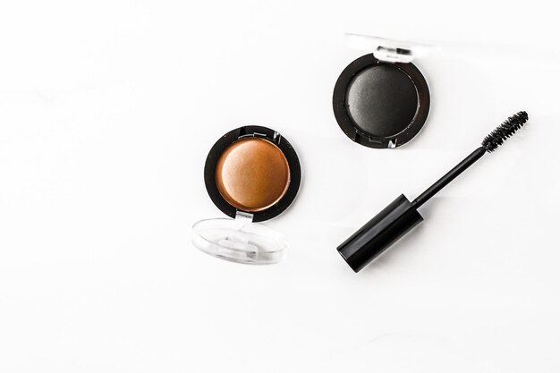 Sombras de ojos delineador negro y rímel sobre fondo de mármol sombras de ojos cosméticos como productos de maquillaje de glamour para el diseño plano de vacaciones de la marca de belleza de lujo