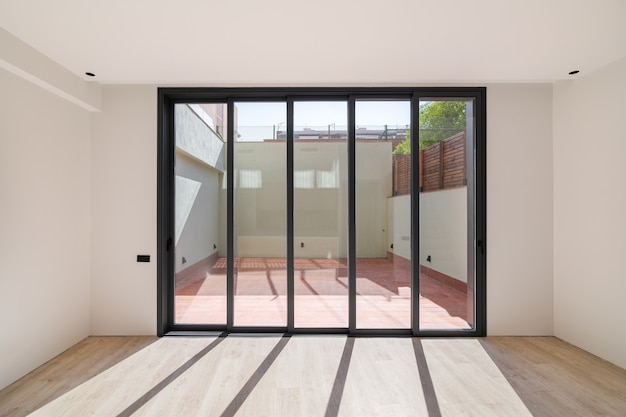 Sombras en el suelo de la luz del sol a través de grandes ventanales habitación nueva con suelo de madera en un ...