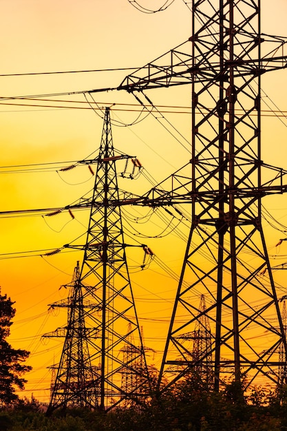 Sombras de torres eléctricas de tensión. Construcciones de tecnología de silueta al atardecer.