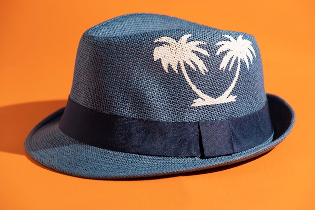 Sombrero azul de verano con dos palmeras sobre fondo naranja