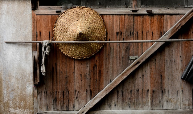 Sombrero de bambú por tejido en ventana de madera vieja