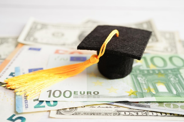 Sombrero de brecha de graduación en billetes de euro y dólar estadounidense dinero Educación tasa de estudio aprendizaje enseñar concepto