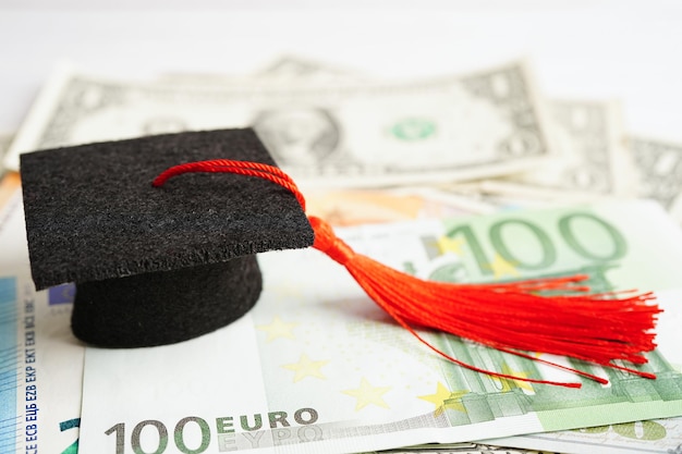 Sombrero de brecha de graduación en billetes de euro y dólar estadounidense dinero Educación tasa de estudio aprendizaje enseñar concepto