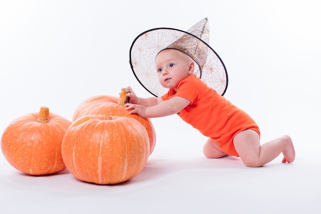 Sombrero de bruja bebé en un blanco sentado delante de calabaza