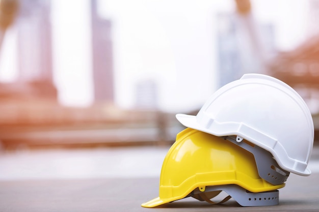 Sombrero de casco de uso de seguridad duro amarillo y blanco en el proyecto en el edificio del sitio de construcción en piso de concreto en la ciudad con luz solar. casco para obrero como ingeniero o trabajador. concepto de seguridad primero.