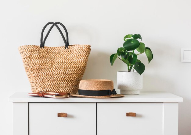 Sombrero de cesta de paja flores caseras en una cómoda blanca en una habitación acogedora y luminosa