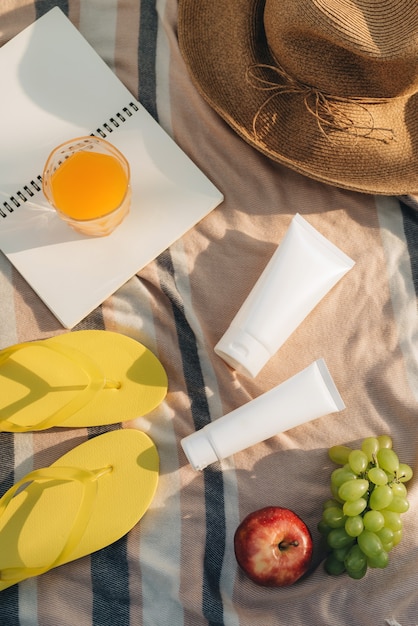 Sombrero, chanclas con frutas, crema solar en el plaid