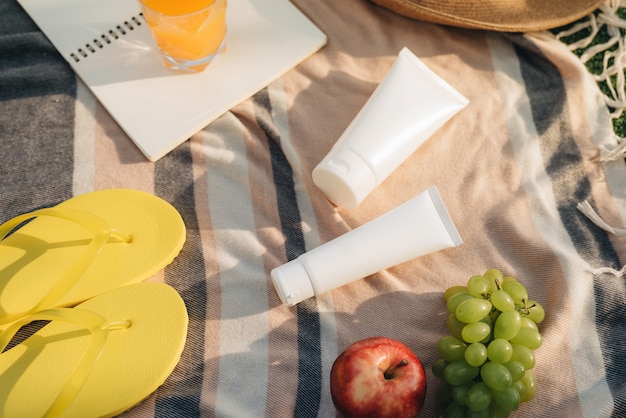 Sombrero, chanclas con frutas, crema solar en el plaid