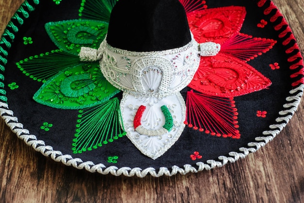 Sombrero charro mexicano sobre mesa de madera. Sombrero típico mexicano con los colores de la bandera mexicana.