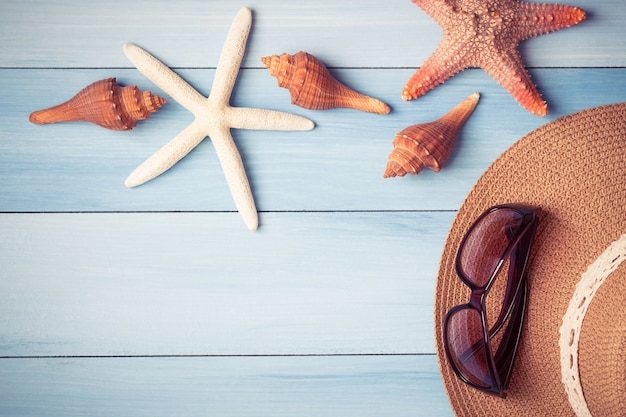 Sombrero y conchas en el piso de madera del concepto azul, verano