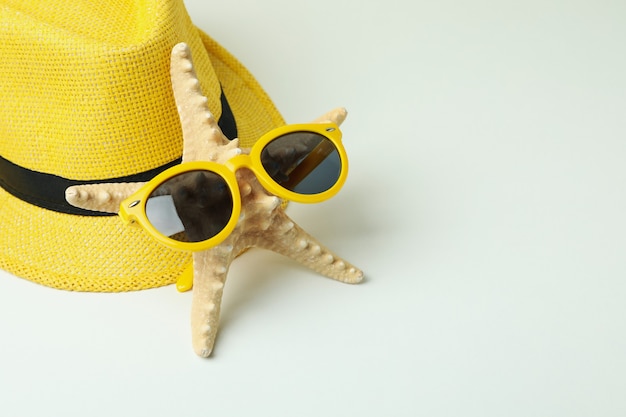 Sombrero, estrella de mar y gafas de sol sobre fondo blanco.