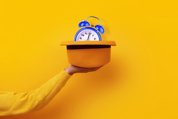 Sombrero de fieltro amarillo de moda con reloj azul en mano