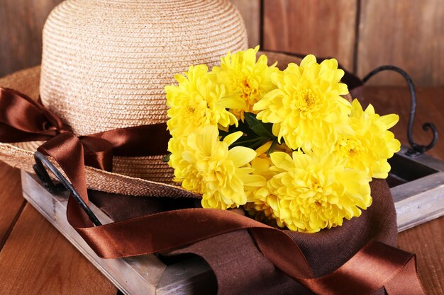 Sombrero con flores sobre fondo de madera