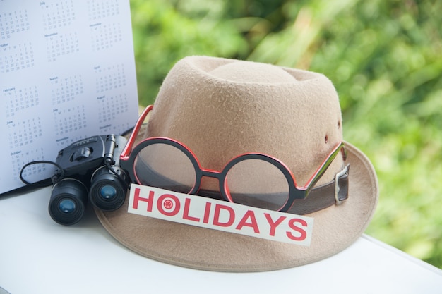 Foto sombrero gafas cámara y vacaciones palabra con calendario