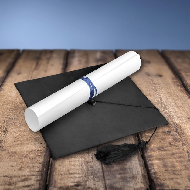 Foto sombrero de graduación y diploma sobre fondo de madera