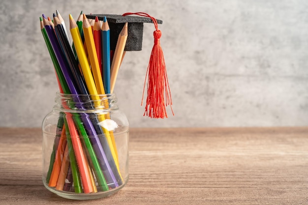 Sombrero de graduación con lápices de colores en el libro con espacio de copia aprendiendo el concepto de educación universitaria