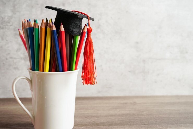 Foto sombrero de graduación con lápices de colores en el libro con espacio de copia aprendiendo el concepto de educación universitaria