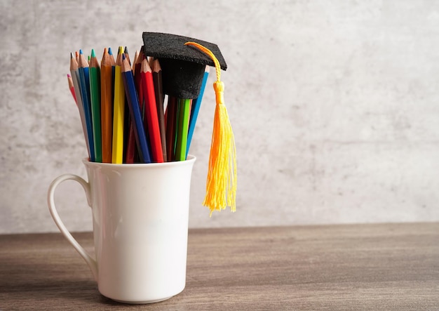 Sombrero de graduación con lápices de colores en el libro con espacio de copia aprendiendo el concepto de educación universitaria