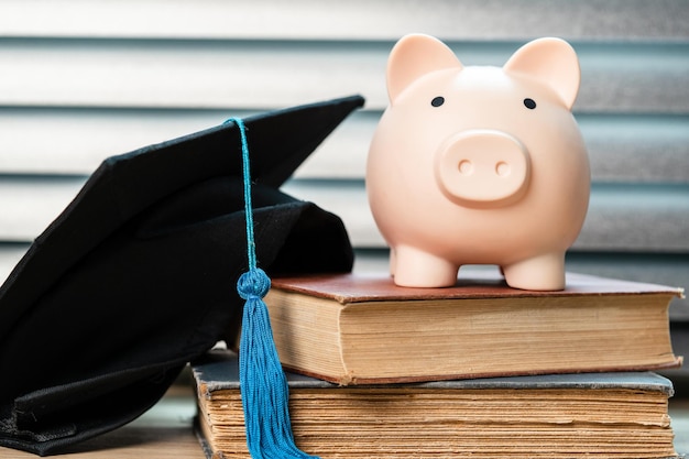 Sombrero de graduación negro y concepto de hucha inversión en educación La graduación ahorra dinero para la educación