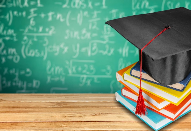 Foto sombrero de graduación en la pila de libros sobre la mesa de madera