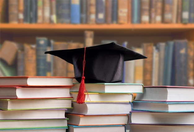 Sombrero de graduación y pilas de libros, vista cercana