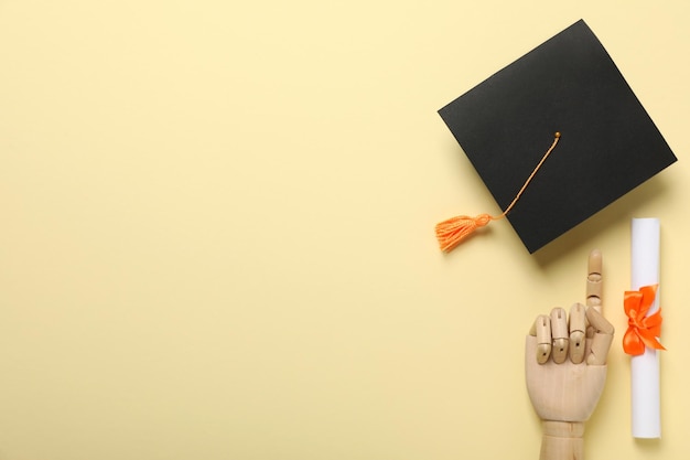 Sombrero de graduado y diploma sobre fondo amarillo