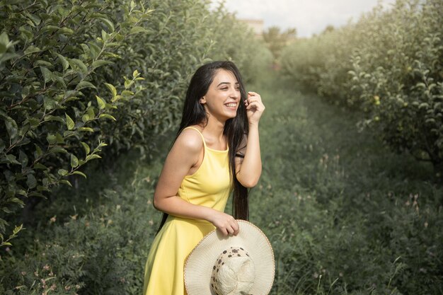 Sombrero de mano de mujer feliz en el jardín